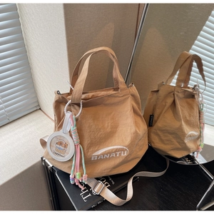 Detail of khaki nylon tote bag featuring white BANATU logo and capybara charm
