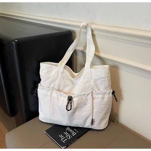 Detail of white multi-pocket nylon tote bag with adjustable drawstring buckles and texture