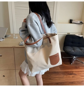 Dettaglio della borsa tote in tela con tasca in pelle marrone e tracolla a contrasto