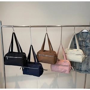 Collection of five nylon tote bags in various colors hanging on a metal rack