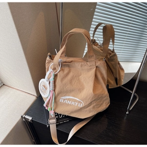 Detail of khaki nylon crossbody bag featuring BANATU logo and capybara charm accessory