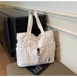 Detail of white nylon tote bag with drawstring pockets and wide shoulder straps