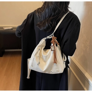 Détail du sac cabas en similicuir blanc crème avec pendentif en cuir marron tressé