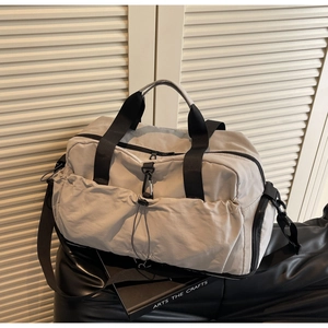 Detail of grey nylon travel bag showing side pocket with drawstring and metal carabiner