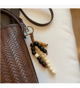 Detail of brown woven texture handbag featuring a chic wooden bead tassel and metal hardware