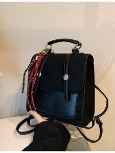 Minimalist black leather mini backpack with textured panels and woven rope charms