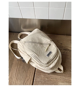Detail view of cream nylon backpack with pleated fabric texture and brand label