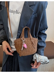Brown leopard print crossbody bag with pink heart charm shown on model in gray suit