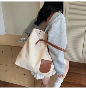 Dettaglio della grande borsa tote in tela beige con tasca in pelle marrone e manici