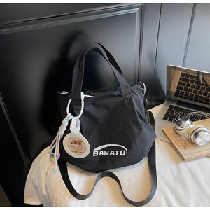 Detail of black nylon tote bag with BANATU logo and cute Capybara charm for commuting