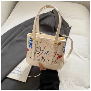 Détail du sac cabas blanc crème avec graffitis de dessins animés et fermoirs dorés