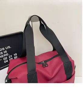 Close-up of red travel bag with reinforced black handles and durable fabric texture