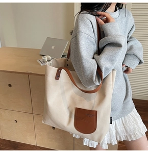 Dettaglio della borsa tote in tela beige con tasca in pelle marrone e tracolla su spalla
