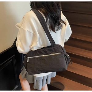 Close-up of black nylon tote bag with silver zipper detail on dark wooden stairs