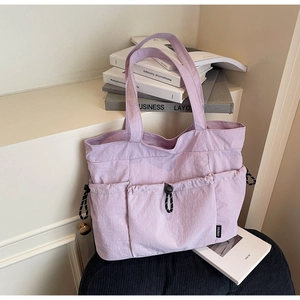 Close-up of light purple nylon tote bag featuring drawstring pockets and sleek brand tag