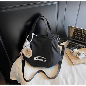 Detailed view of black nylon shoulder bag with BANATU logo and cute Capybara charm