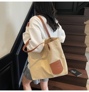 Dettaglio della borsa tote in tela con tasca in pelle marrone e logo del marchio