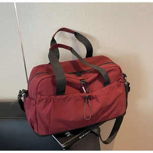 Detail of burgundy travel bag showing durable nylon texture and adjustable drawstring pocket