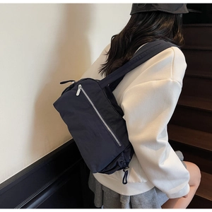 Detail of dark blue nylon tote bag with silver metal zipper and drawstring on stairs
