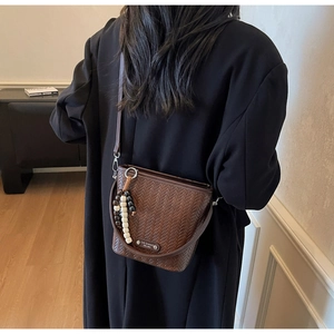 Detail of dark brown woven bucket bag featuring wooden beads and textured vintage finish