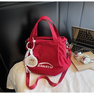 Red nylon tote bag with Banatu logo and cute capybara charm on a stylish commuter desk