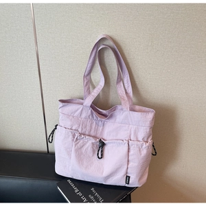 Detail of light purple nylon tote bag featuring drawstring pockets and sporty cord accents