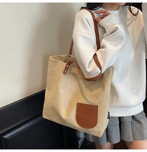 Dettaglio della borsa tote in tela beige con manici in pelle marrone e toppa decorativa