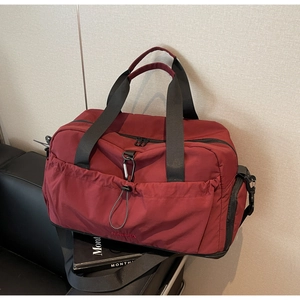 Detail of burgundy waterproof nylon travel bag with drawstring front pocket and strap