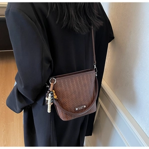Detailed view of a brown woven bucket bag with stylish wooden bead charms on the side