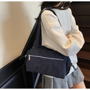 Detail of dark blue nylon shoulder bag featuring silver metal zipper and drawstring