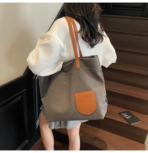 Dettaglio della borsa tote in tela taupe con manici in pelle marrone e inserto arancione