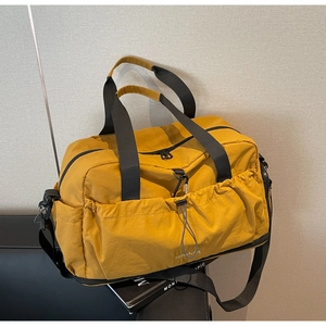 Macro detail of mustard yellow nylon travel bag with functional drawstring pockets and straps