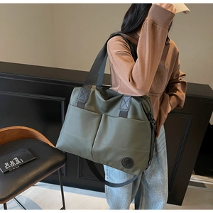 Detail of olive green nylon backpack with front pockets and adjustable shoulder strap