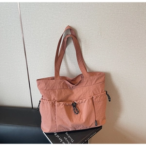 Detail of dusty rose nylon tote bag with drawstring pockets and water-resistant texture