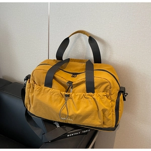 Detailed shot of yellow nylon travel bag with elastic drawstrings on a black leather table