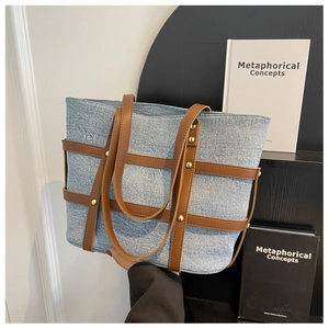 Detail of denim tote bag with brown leather straps and gold stud rivets decoration