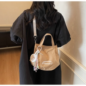 Close-up of khaki tote bag with BANATU logo and cute Capybara charm with tassel details
