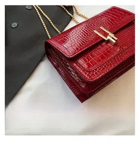 Detail of red crocodile texture flap bag with gold chain strap and metal clasp