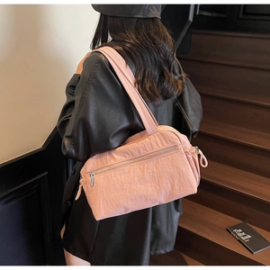 Detail of pink nylon tote bag featuring crinkled texture and silver zipper pocket