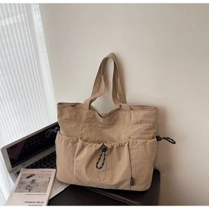 Macro shot of khaki nylon tote bag featuring drawstring pockets and wrinkled texture details