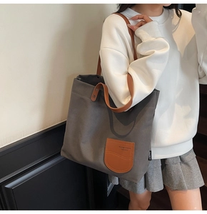 Dettaglio della borsa tote in tela grigia con tasca in pelle marrone e rilievo