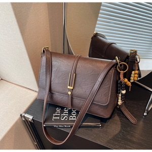Detail of vintage brown textured leather shoulder bag with gold clasp and beaded tassel