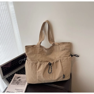 Close-up of khaki nylon tote bag with three drawstring pockets and braided cord details