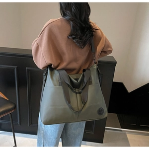Olive green nylon tote bag shown on model highlighting large capacity and durable strap