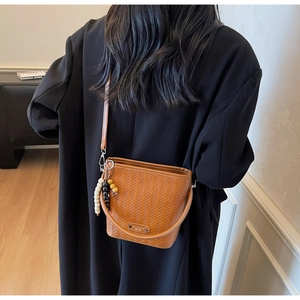 Detailed back view of a brown bucket bag featuring woven textures and beaded charm