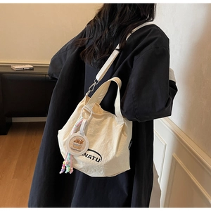 Detail view of canvas tote bag with NATU lettering and cute capybara pendant on shoulder strap
