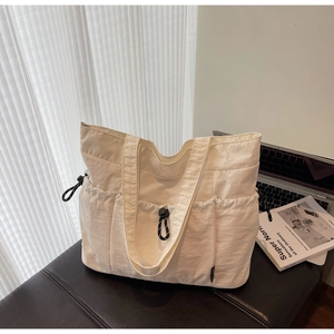 Detail of white nylon tote bag with drawstring pockets on a leather bench setup