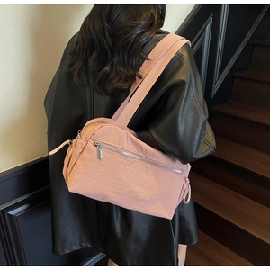 Pink minimalist nylon tote bag with wide straps and zipper pocket shown on a shoulder