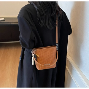 Close-up of woven texture bucket bag with wooden bead handle on a black wool coat
