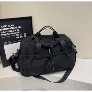 Detail of black waterproof nylon travel bag with drawstring pockets and adjustable strap